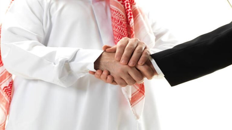 رجل أعمال سعودي بالشماغ الأحمر يصافح شريكًا دوليًا